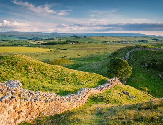 sloping green hills with stone wall