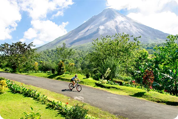 cyclist riding by large mountain